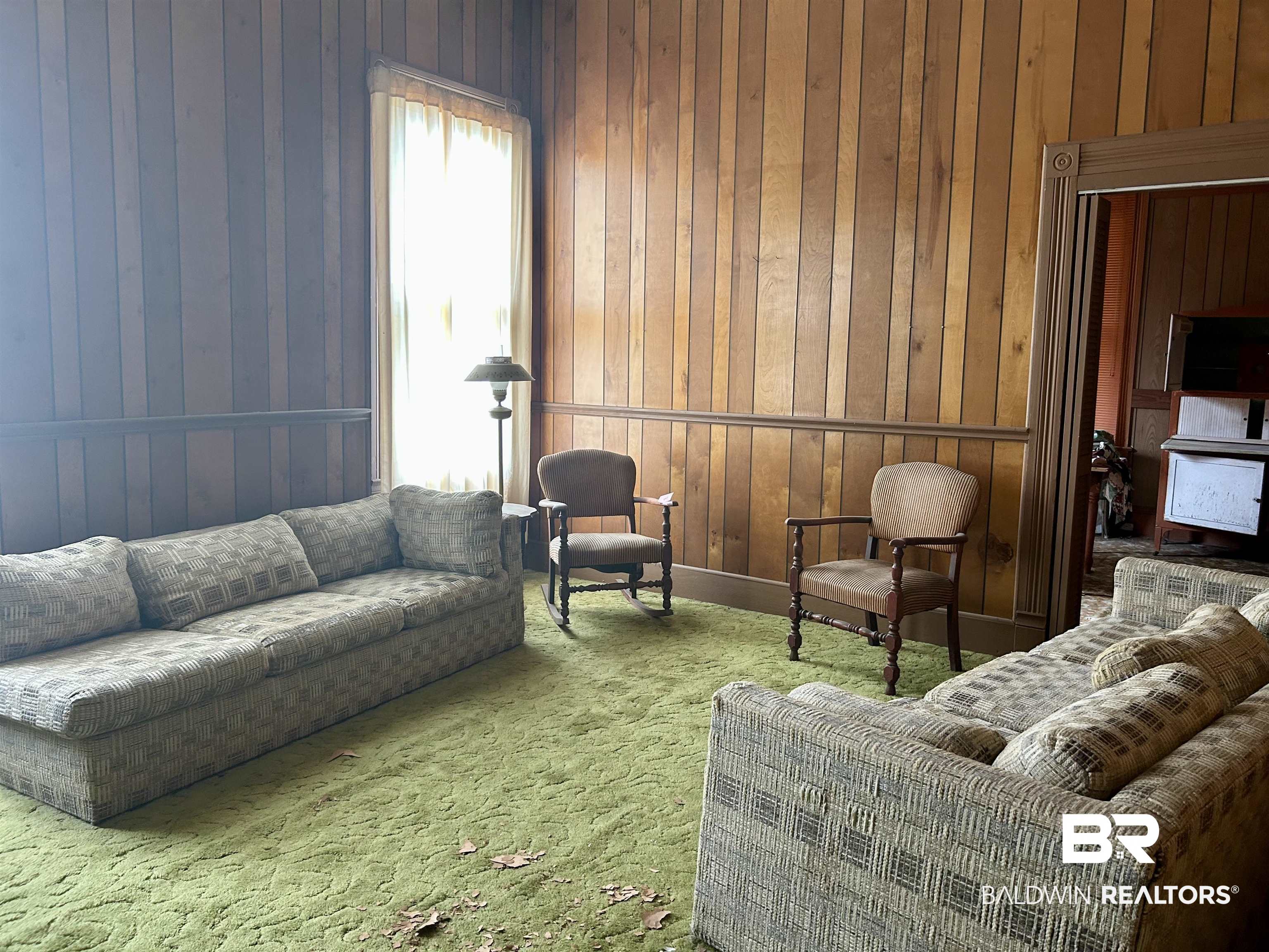 302 Stocking Street Mobile, AL 36604 - Photo 9 of 31 Interior space featuring wood paneling, a large window with sheer curtains, and a doorway with detailed trim