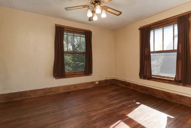 a view of an empty room with wooden floor and a window