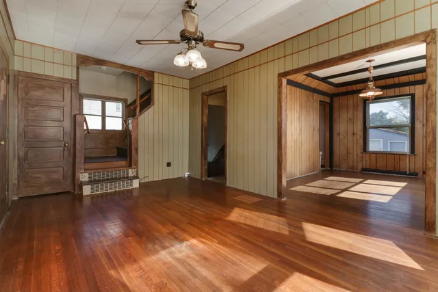 a view of empty room with wooden floor and fan