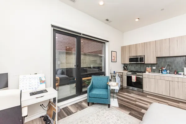 a living room with stainless steel appliances furniture a rug and a kitchen view