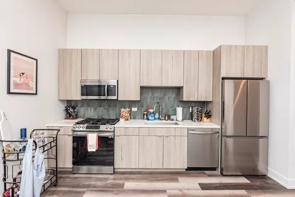 a kitchen with stainless steel appliances a refrigerator a stove a sink and white cabinets