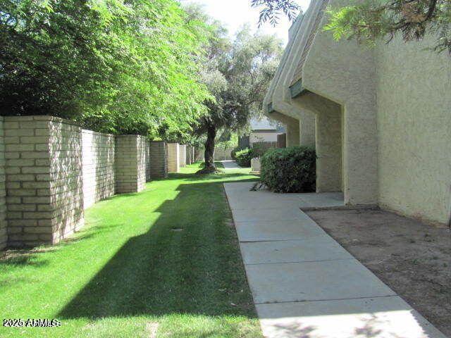 a backyard of a house with plants and large tree