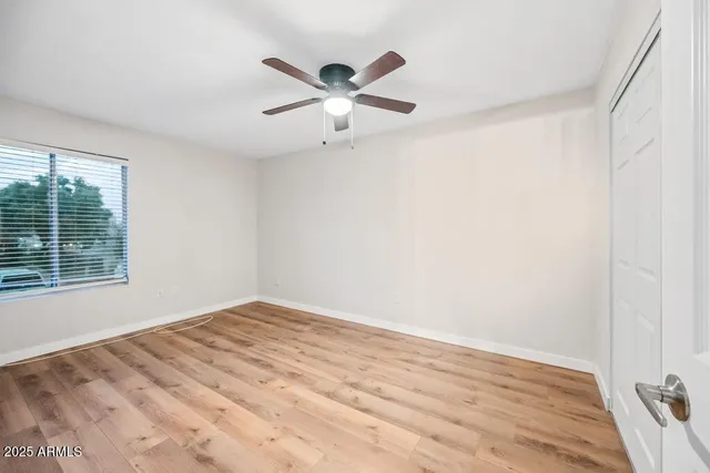 a view of empty room with wooden floor and fan