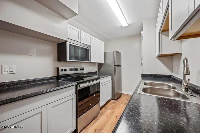 a kitchen with granite countertop a sink stainless steel appliances and cabinets