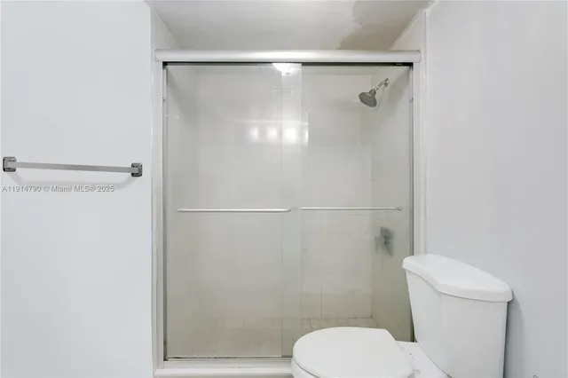 a white toilet sitting next to a shower