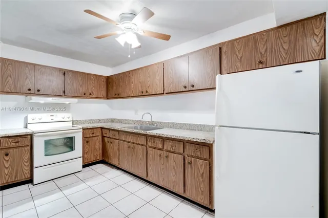 a kitchen with a sink a refrigerator and cabinets