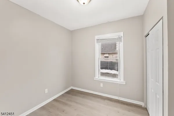 a view of an empty room with closet and a window