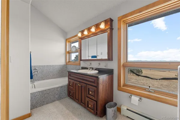 a bathroom with a granite countertop sink and a bathtub