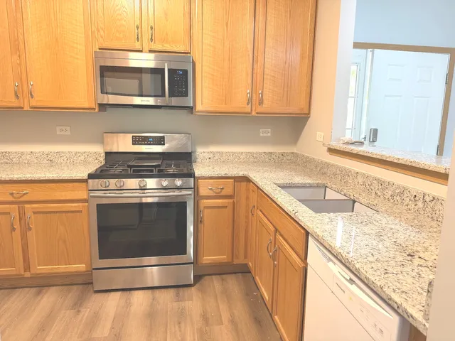 a kitchen with granite countertop a refrigerator stove and oven