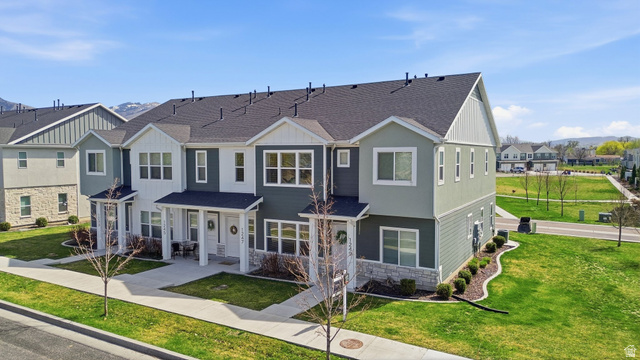 1247 West 1820th Street South Logan, UT 84321 - Photo 1 of 21 Townhome with a porch, a front lawn, stone siding, and a shingled roof