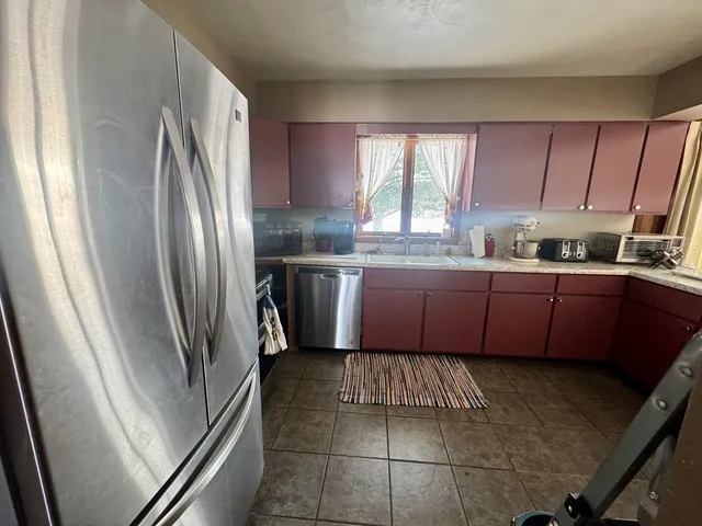 a kitchen with stainless steel appliances granite countertop a refrigerator a sink a stove a washer dryer and a cabinets