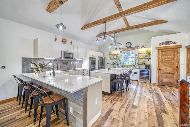 a kitchen with stainless steel appliances granite countertop a dining table chairs stove and granite counter top