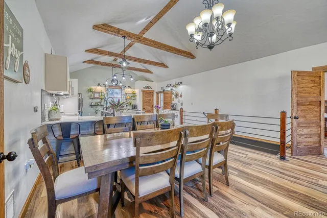 a dining room with wooden floor a chandelier a wooden table and chairs