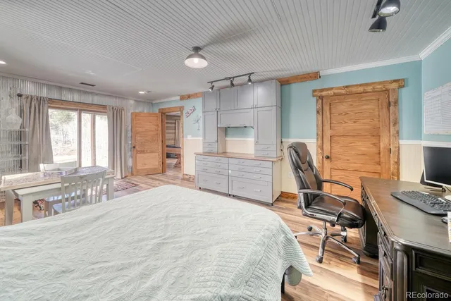 a bedroom with a bed and a desk in it with wooden floor