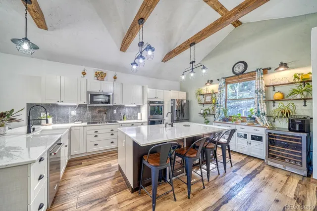 a kitchen with stainless steel appliances granite countertop a table chairs and white cabinets