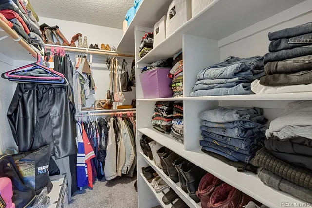 a view of walk in closet with clothes and shoes