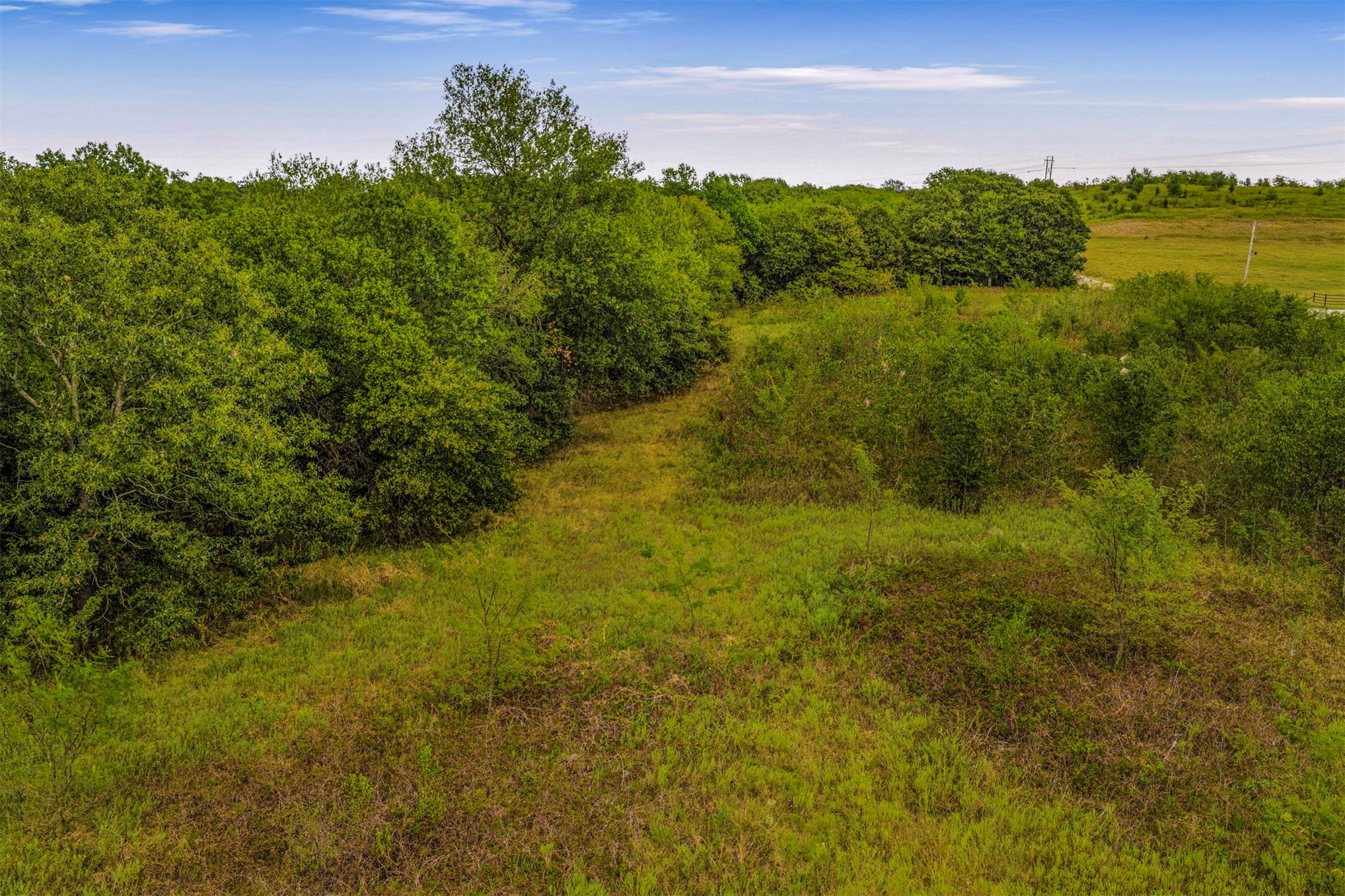 King Road Claremore, OK 74019 - Photo 42 of 45 Expansive land parcel featuring dense treelines, open grassy areas, and a clear sky backdrop