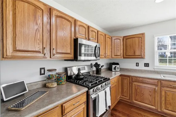 a kitchen with stainless steel appliances granite countertop a stove a sink dishwasher and cabinets with wooden floor