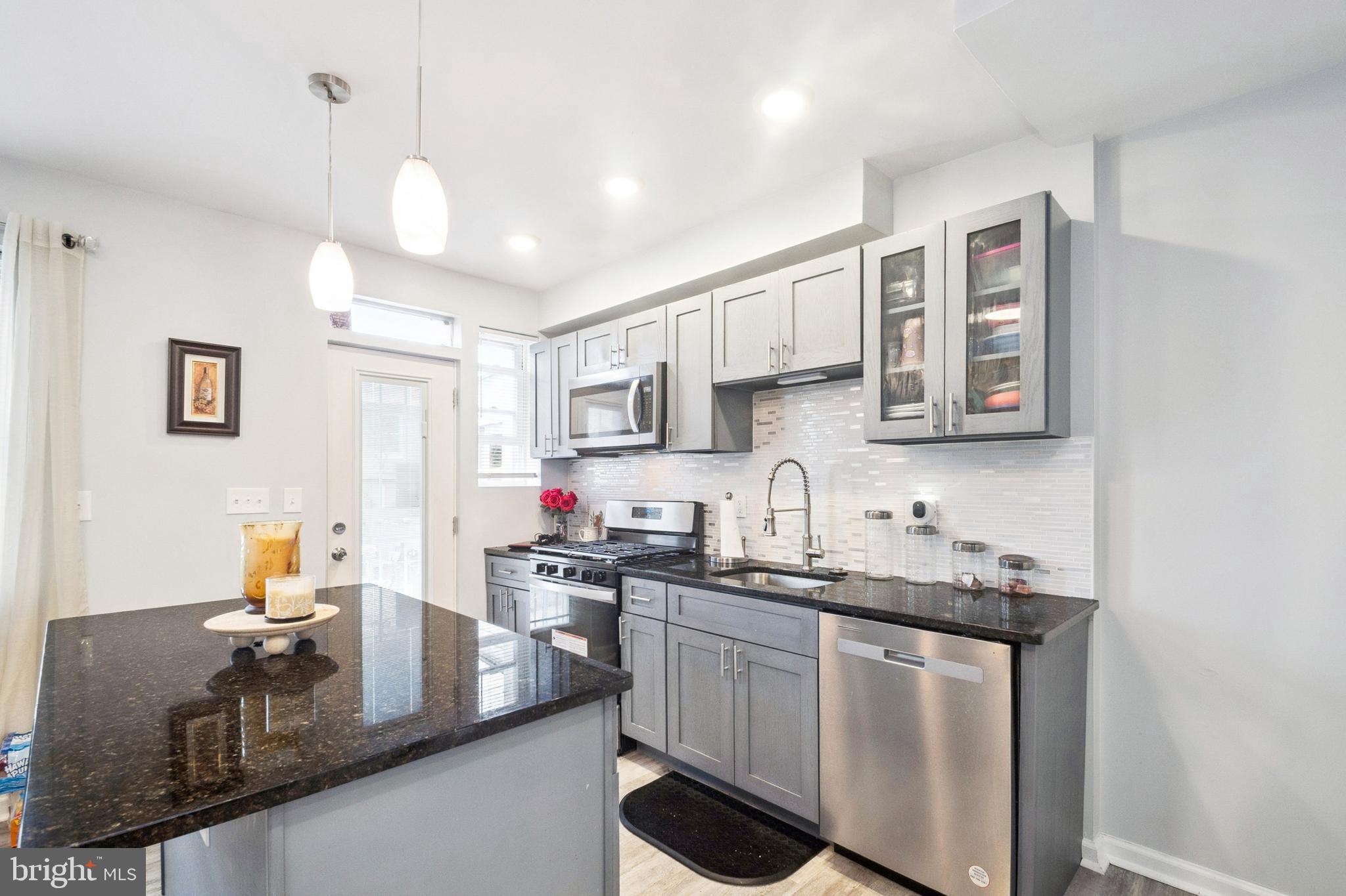 3404 Lyndale Avenue Baltimore, MD 21213 - Photo 5 of 25 a kitchen with a sink dishwasher a stove and white cabinets with wooden floor