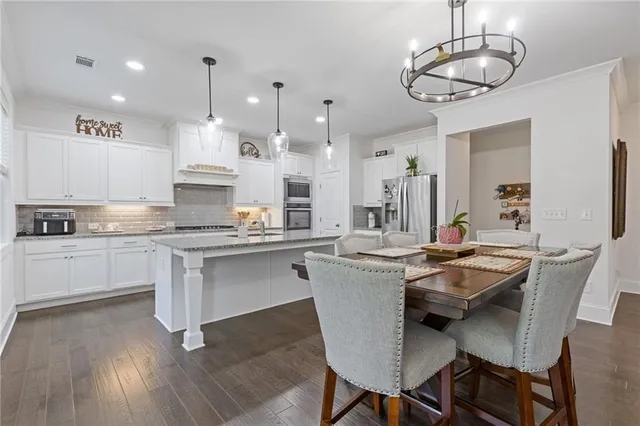 a view of a dining room with furniture a kitchen and chandelier