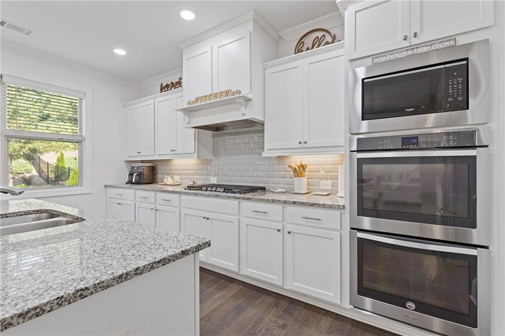 4867 Hunters Grove Way Sugar Hill, GA 30518 - Photo 23 of 61 a kitchen with granite countertop white cabinets stainless steel appliances and a counter space