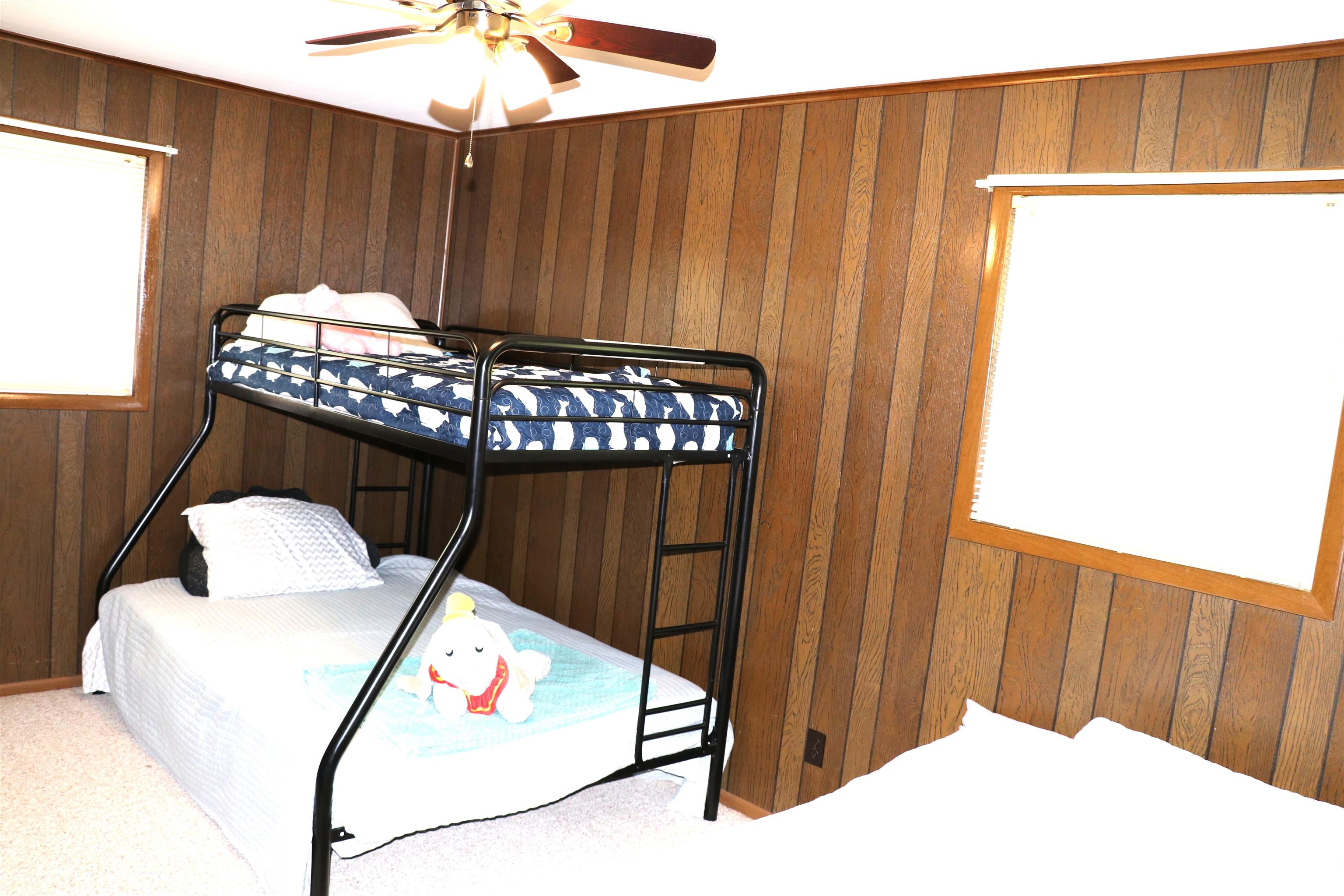 160 Patrick Drive Springville, TN 38256 - Photo 11 of 34 Interior room featuring wood paneling on walls, two windows with wood trim, and a ceiling fan with integrated lighting