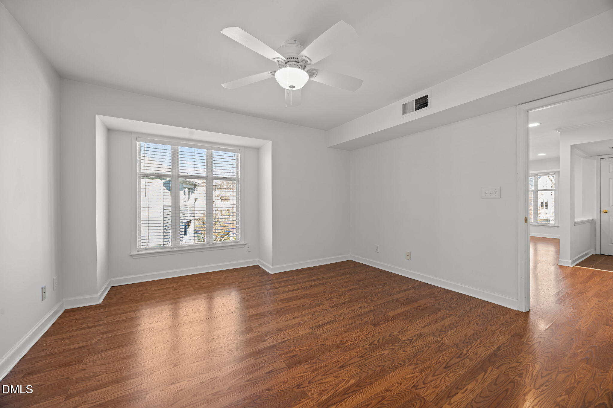 1210 Westview Lane, Unit 309 Raleigh, NC 27605 - Photo 18 of 42 an empty room with wooden floor chandelier fan and windows