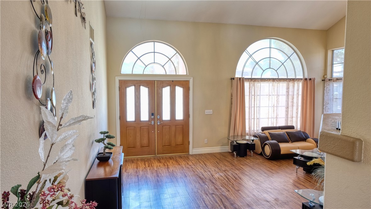 3704 North Campbell Road Las Vegas, NV 89129 - Photo 5 of 38 Ornate arched windows complement a grand double-door entry, illuminating a wide-plank wood floor.