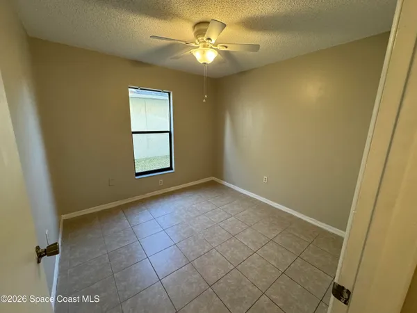 an empty room with windows and fan