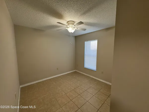 an empty room with a window and a fan