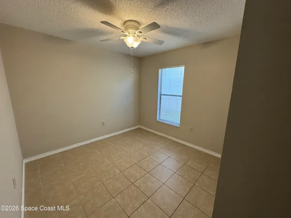 an empty room with windows and fan