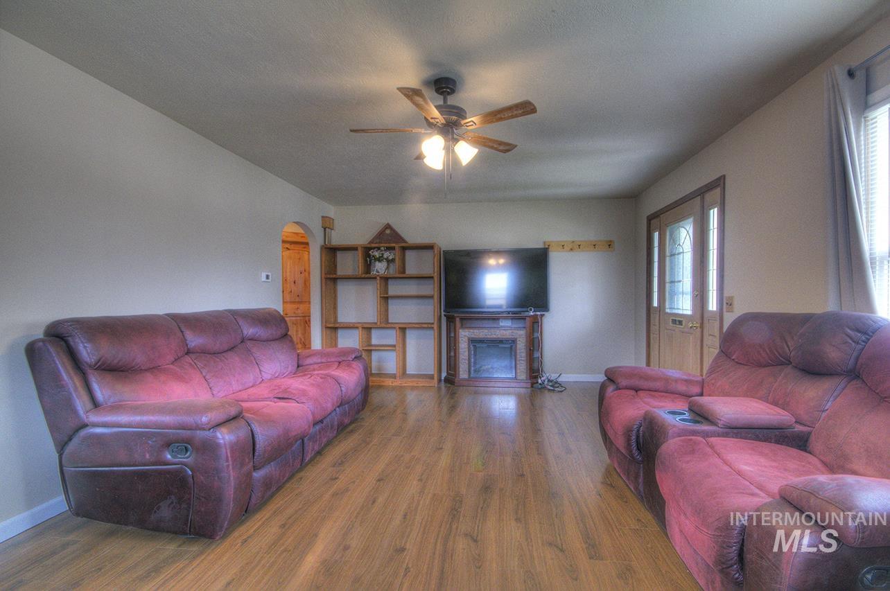 351 West Main Street South Vale, OR 97918 - Photo 18 of 33 Living area featuring wood-finish flooring, a ceiling fan with integrated lighting, and a decorative fireplace with a mantel