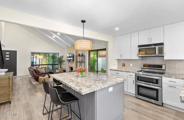 a kitchen view with stainless steel appliances granite countertop a refrigerator a stove and a sink