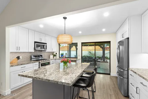 a kitchen with kitchen island granite countertop a sink a stove a dining table and chairs with wooden floor