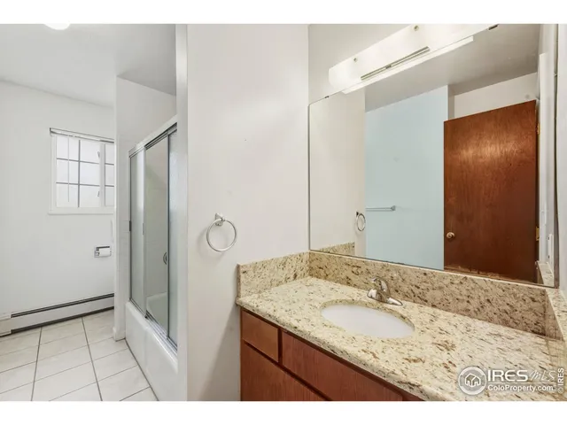 a bathroom with a granite countertop sink a mirror and a shower