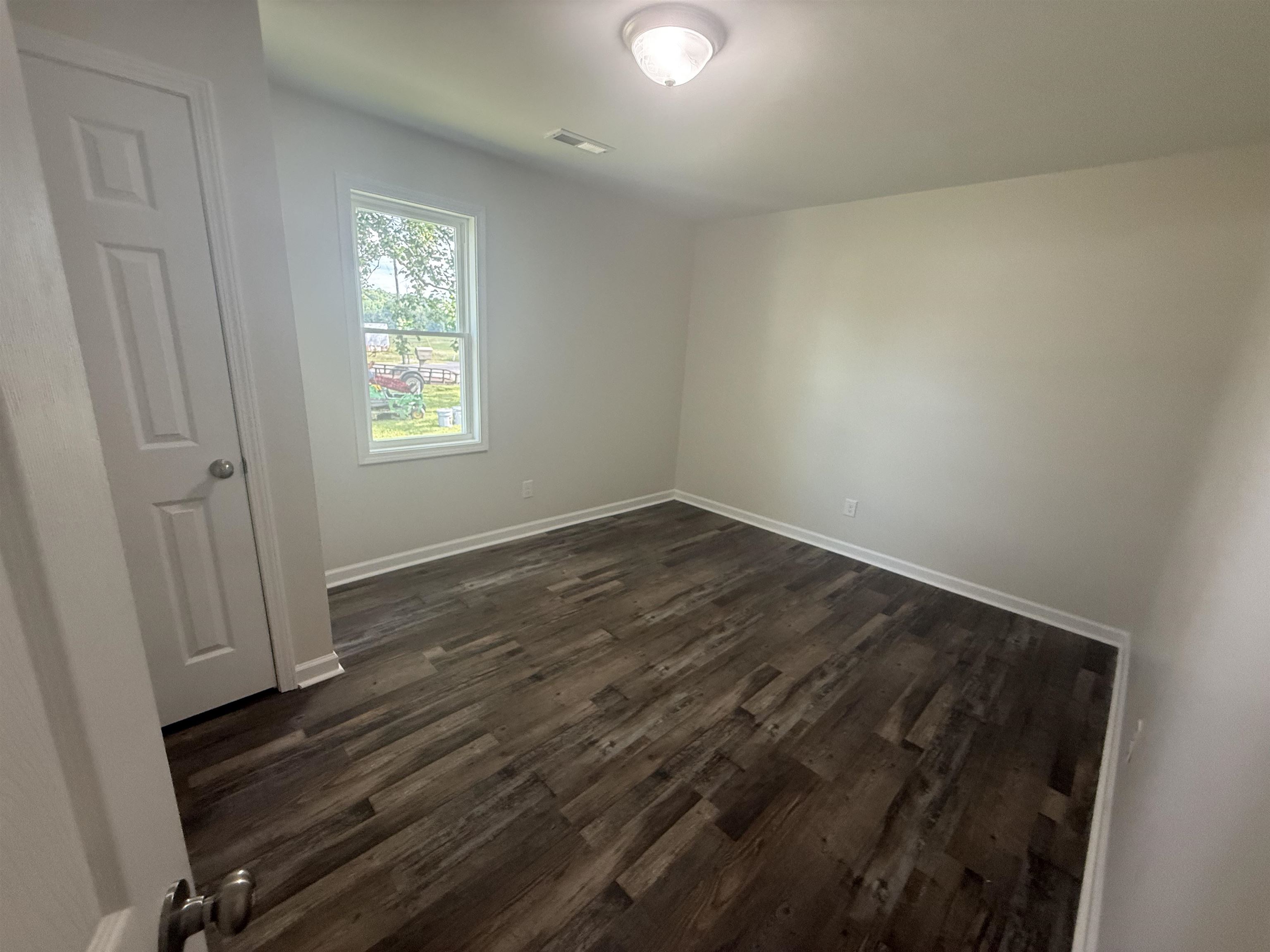 170 Leapwood Road Enville, TN 38332 - Photo 26 of 33 Room featuring wood-finish flooring, a single window, white baseboards, and a flush mount ceiling light fixture