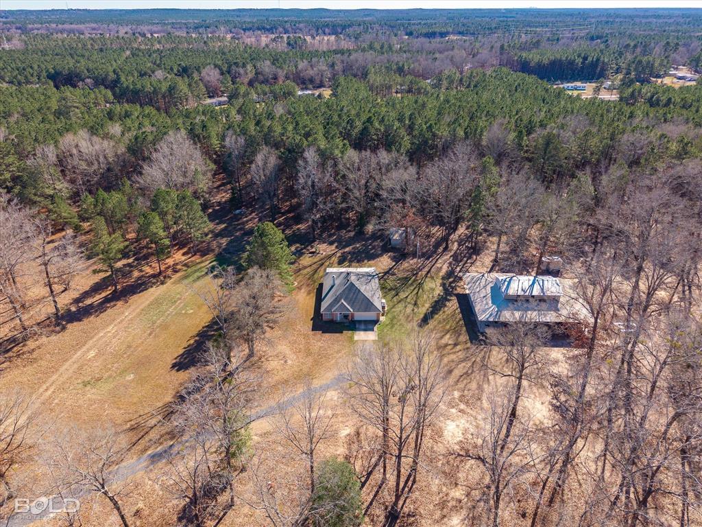 136 Scarborough Road Benton, LA 71006 - Photo 1 of 32 Expansive property featuring a central residence with a gabled roof and a separate outbuilding, all surrounded by mature trees
