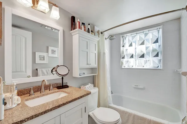 a bathroom with a granite countertop sink mirror vanity and toilet