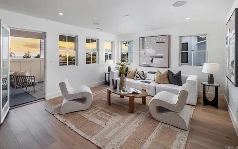a living room with furniture large window and wooden floor