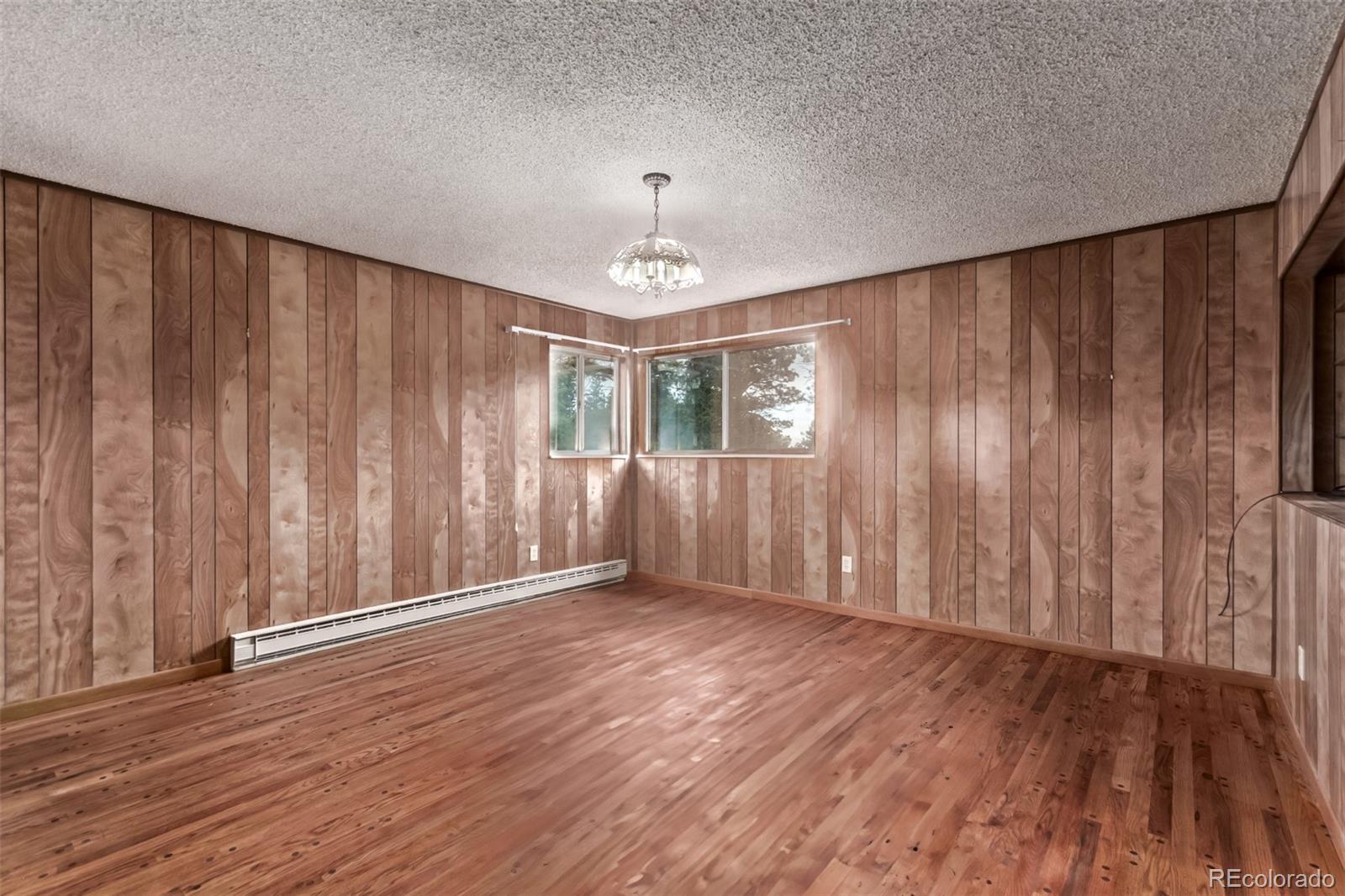 15481 Rist Canyon Road Bellvue, CO 80512 - Photo 17 of 50 an empty room with wooden floor chandelier fan and windows
