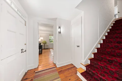 a view of a hallway with wooden floor and a bathroom