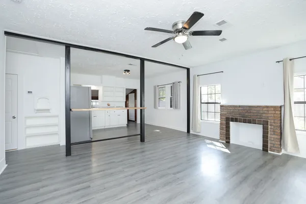 a view of a livingroom with a fireplace a ceiling fan and wooden floor