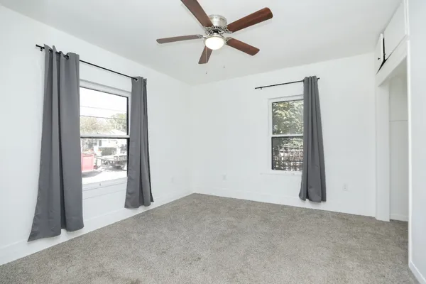 an empty room with windows and fan