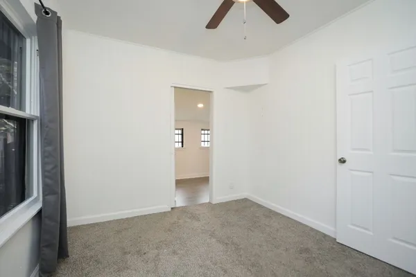 an empty room with ceiling fan and window