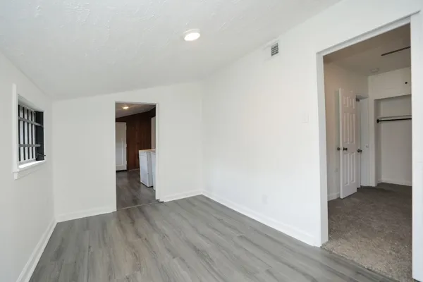 a view of an empty room with wooden floor and a window