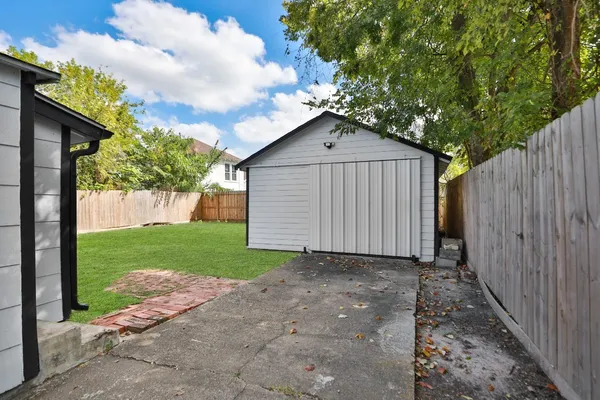 a view of a house with a small yard plants and a large tree
