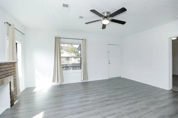 an empty room with wooden floor and a ceiling fan
