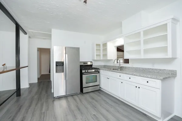a kitchen with granite countertop white cabinets and stainless steel appliances