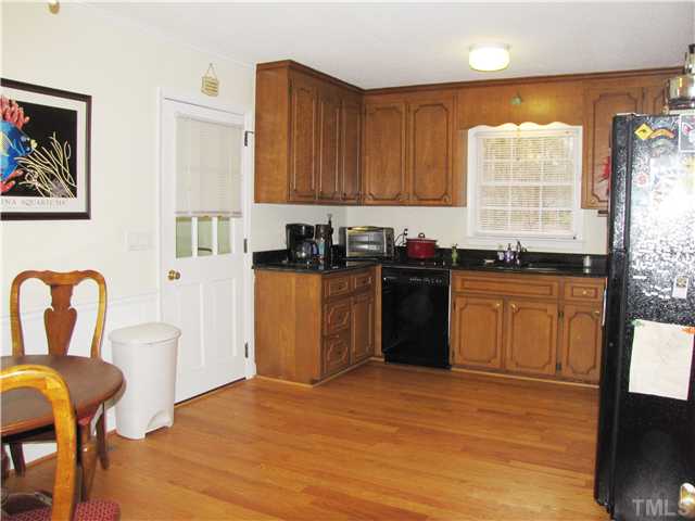 103 Dabney Road Cary, NC 27511 - Photo 8 of 25 a kitchen with stainless steel appliances granite countertop a stove top oven a sink a dining table and chairs with wooden floor