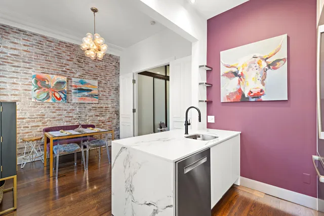 a utility room with stainless steel appliances kitchen island granite countertop a stove a sink and a dining table with wooden floor